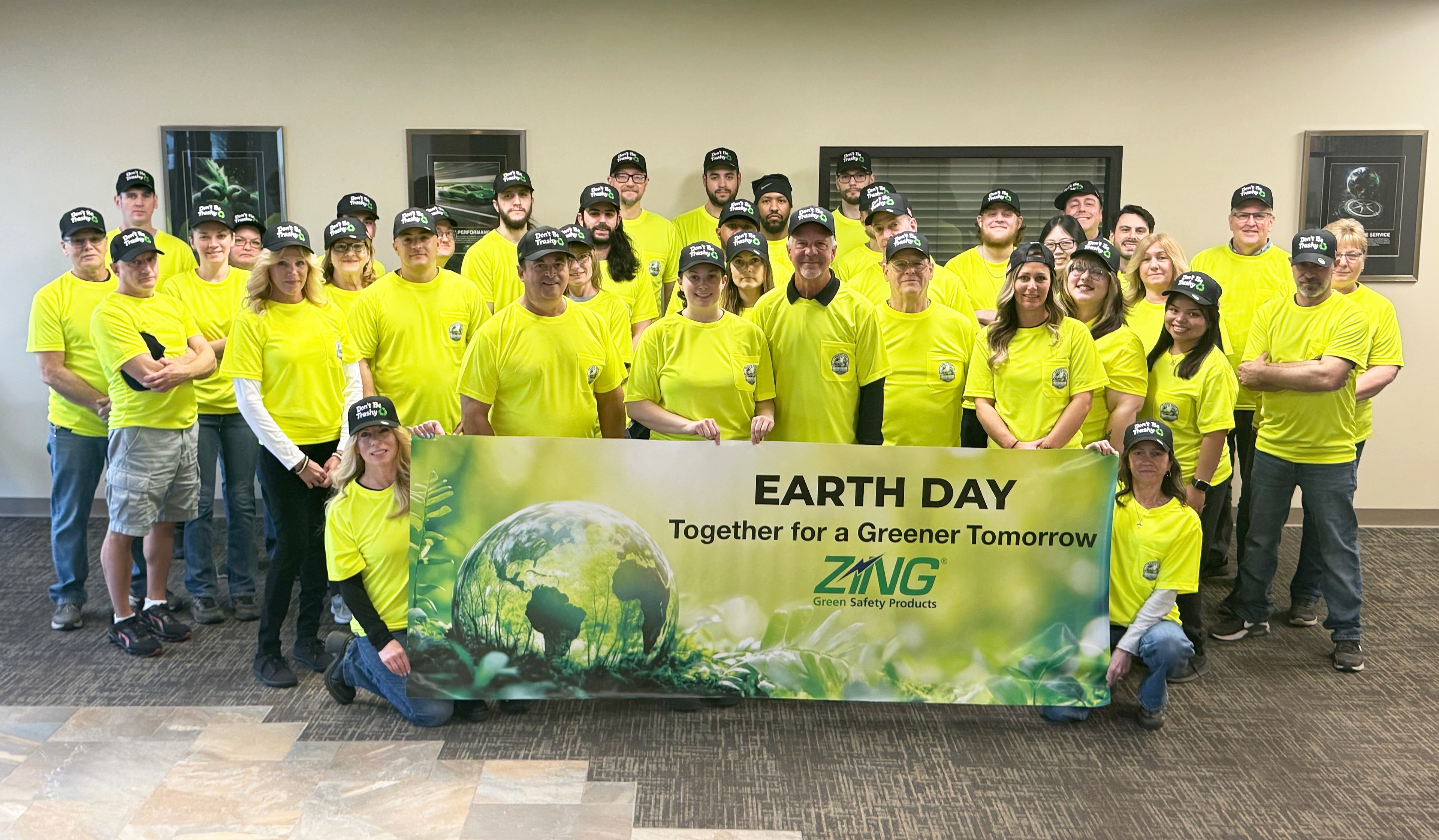 Zing Green Products employees wearing yellow shirts and holding an Earth Day banner