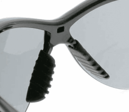 Close-up detail of frameless safety glasses with integrated nose piece and temple connection